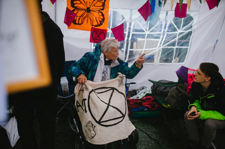 femme âgée du clergé avec une bannière noire et blanche de la Rébellion del'extinction discutant avec un jeune homme lors d'unemanifestation
